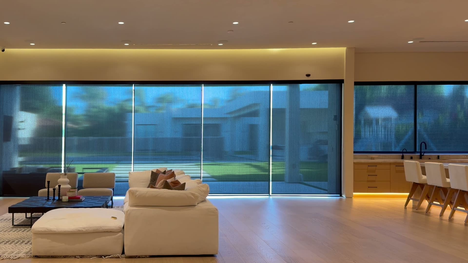 Motorized solar shades rising across a wall of sliding glass doors in a modern Los Angeles living room